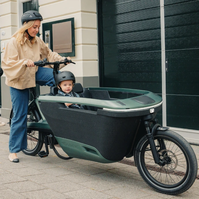 Eine Frau steigt auf ein Lovens Explorer 2 auf. Im Lastenrad sitzt ein Kind.