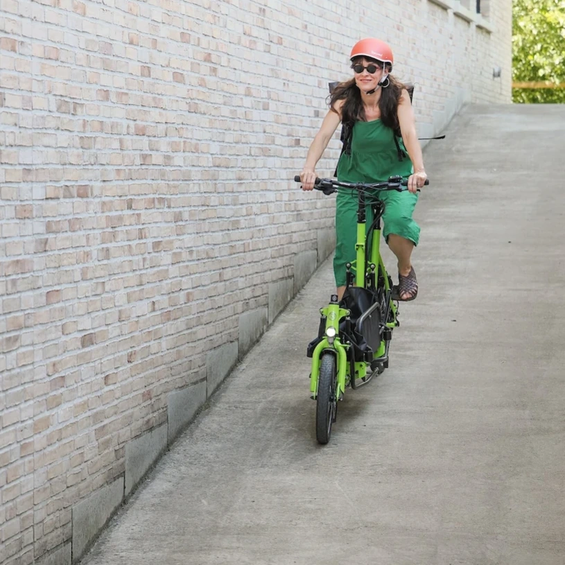 A woman is riding a Radkutsche VIVID downhill. The front basket is folded down.